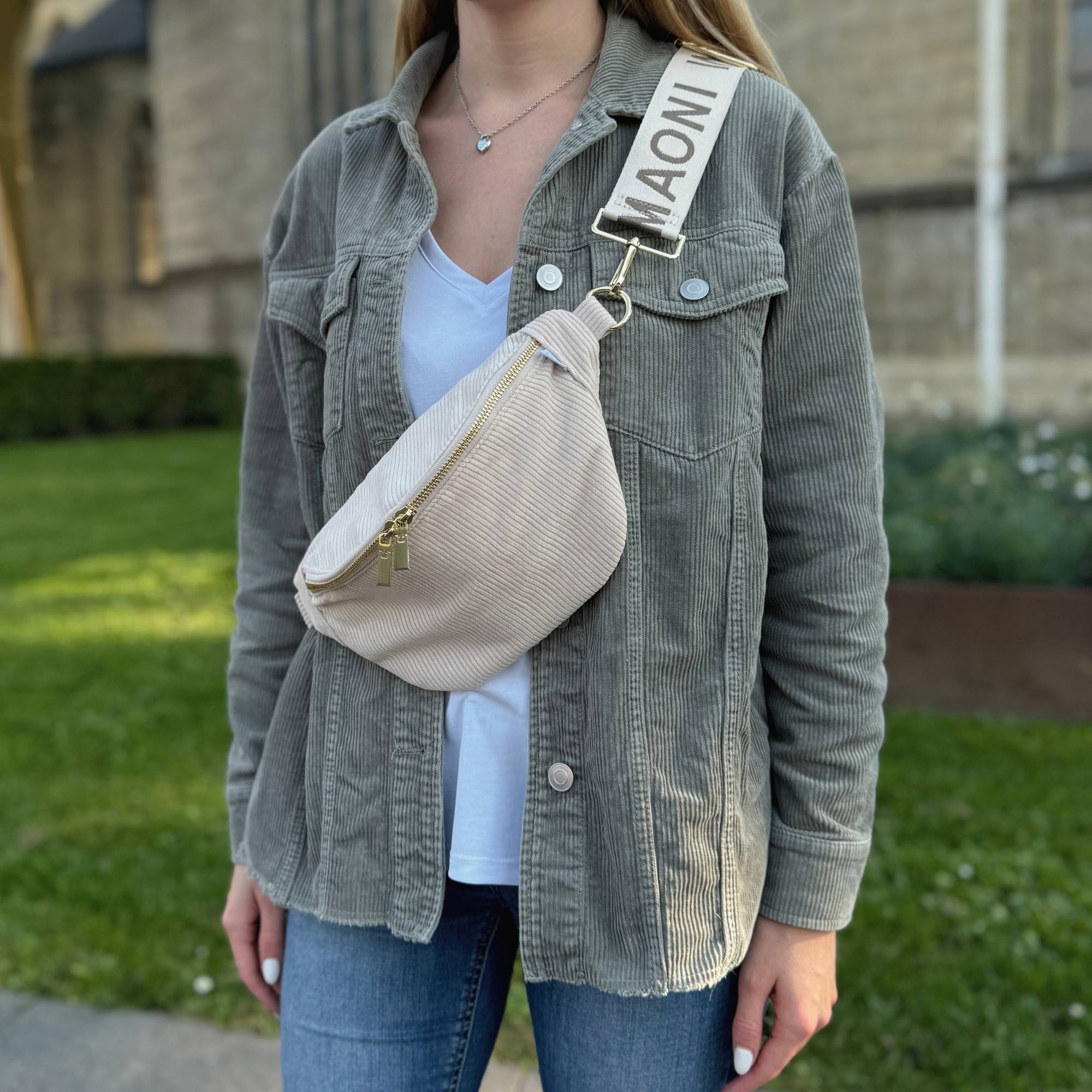 Frau präsentiert beige Cord Bauchtasche mit MAONI Taschengurt.