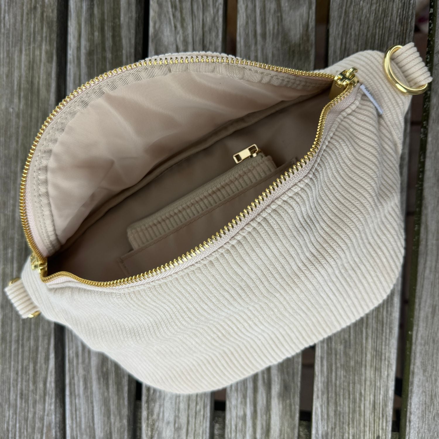 Innenansicht der MAONI Cord Bauchtasche: Offene Handtasche mit praktischem offenen Fach, in dem das Cord Etui steckt, präsentiert auf einem Holz Tisch.