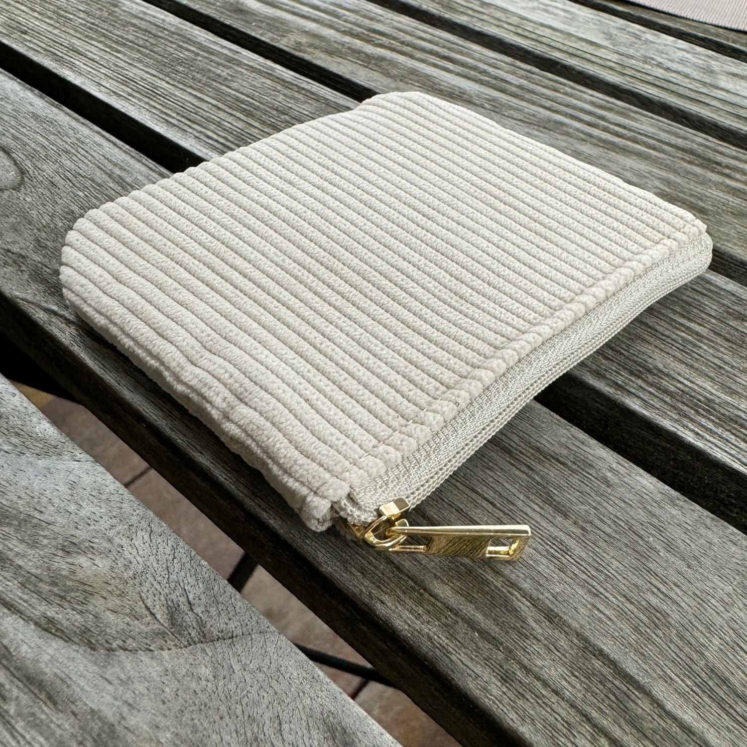 Cord etui in beige liegt auf Holztisch.