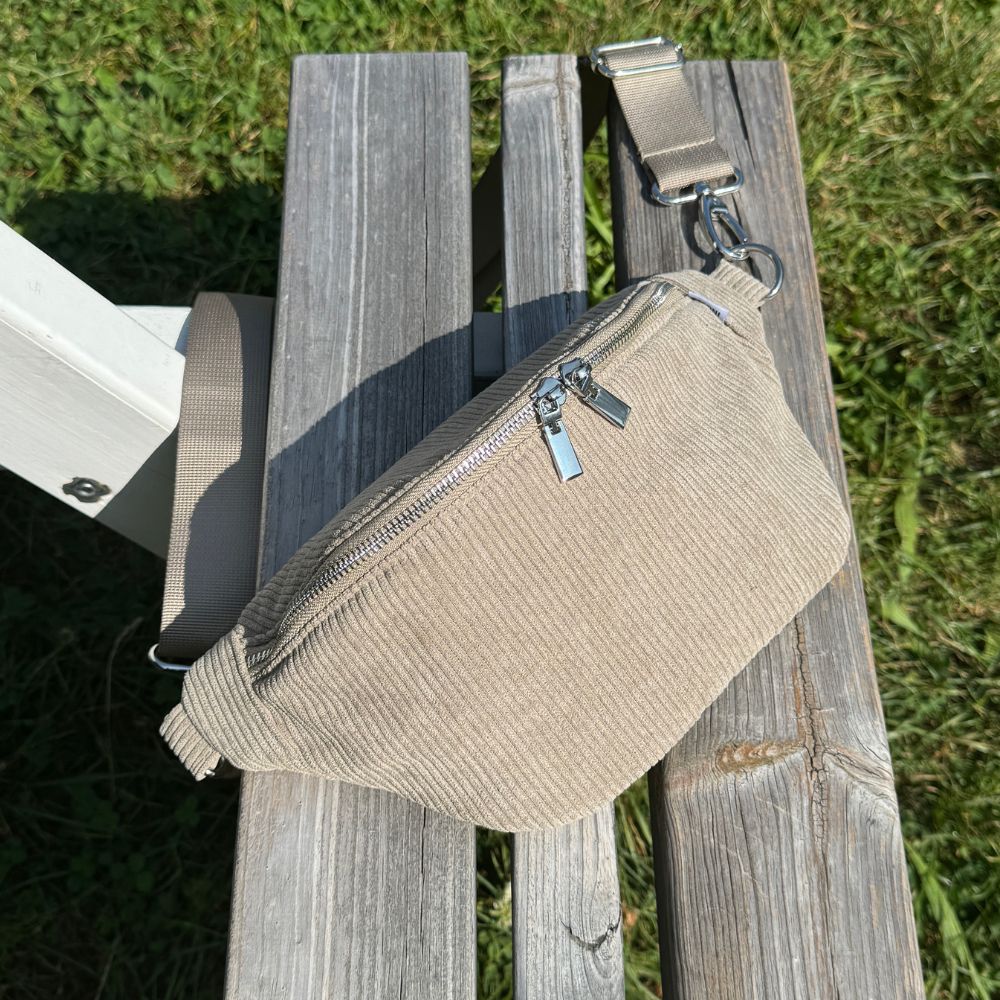 Sommerliches Setting auf Bank mit Wiese: Unsere Cord Bauchtasche in grün perfekt in Szene gesetzt.