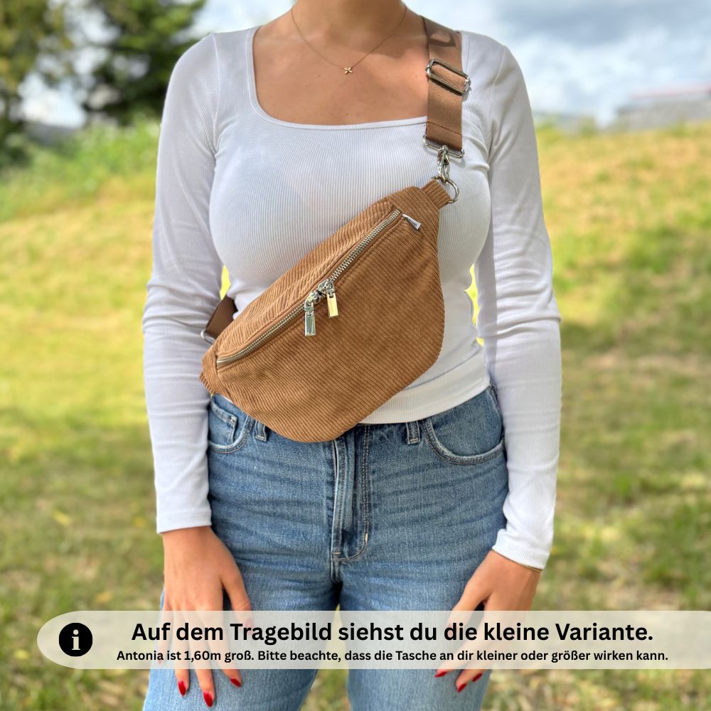 Braune Cord-Bauchtasche in kleiner Variante, getragen von Frau in Jeans und weißem Oberteil – Model ist 1,60 m groß, Größenverhältnis im Bild gut erkennbar