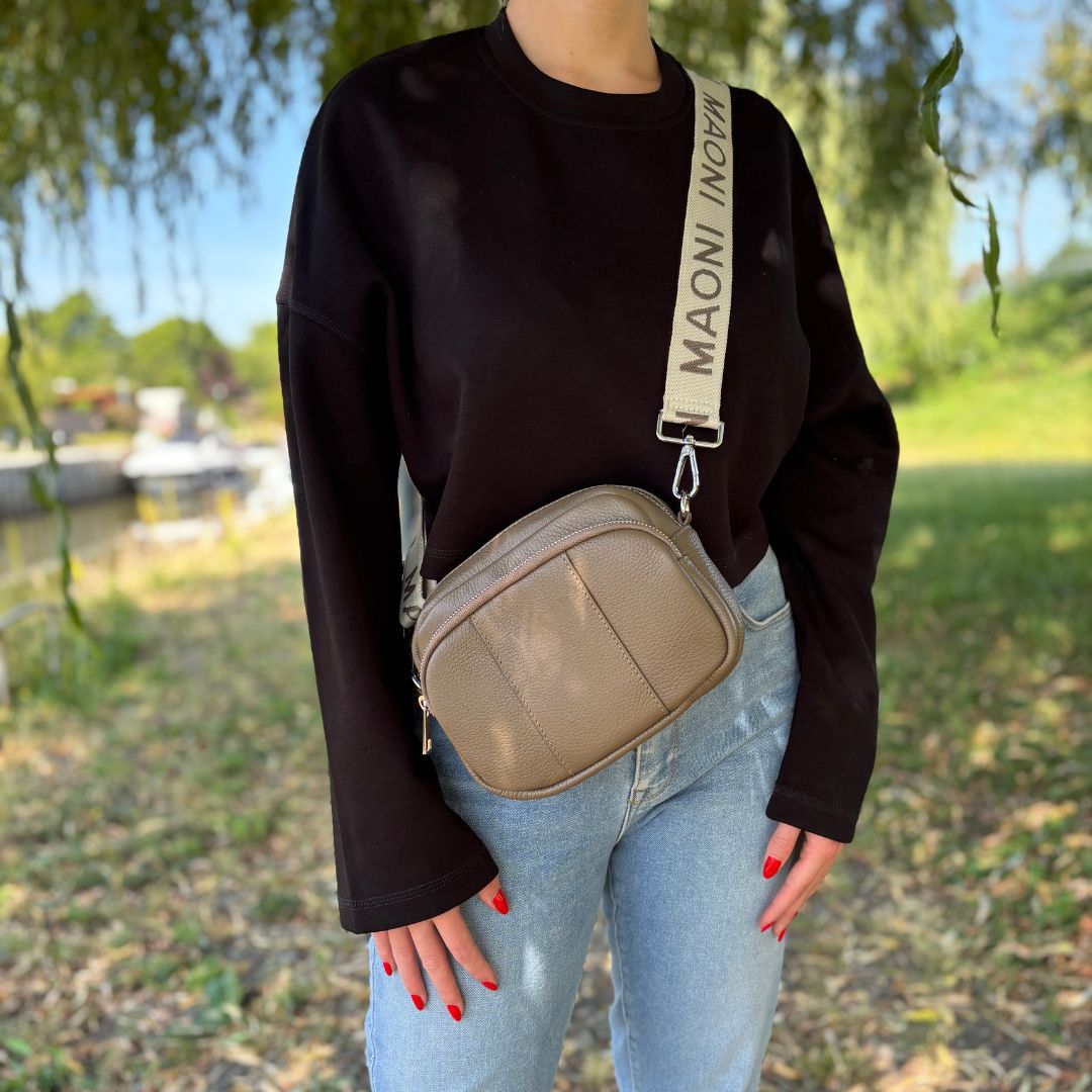 Damen-Crossbody-Bag in natürlicher Umgebung kombiniert mit Jeans und schwarzem Pullover