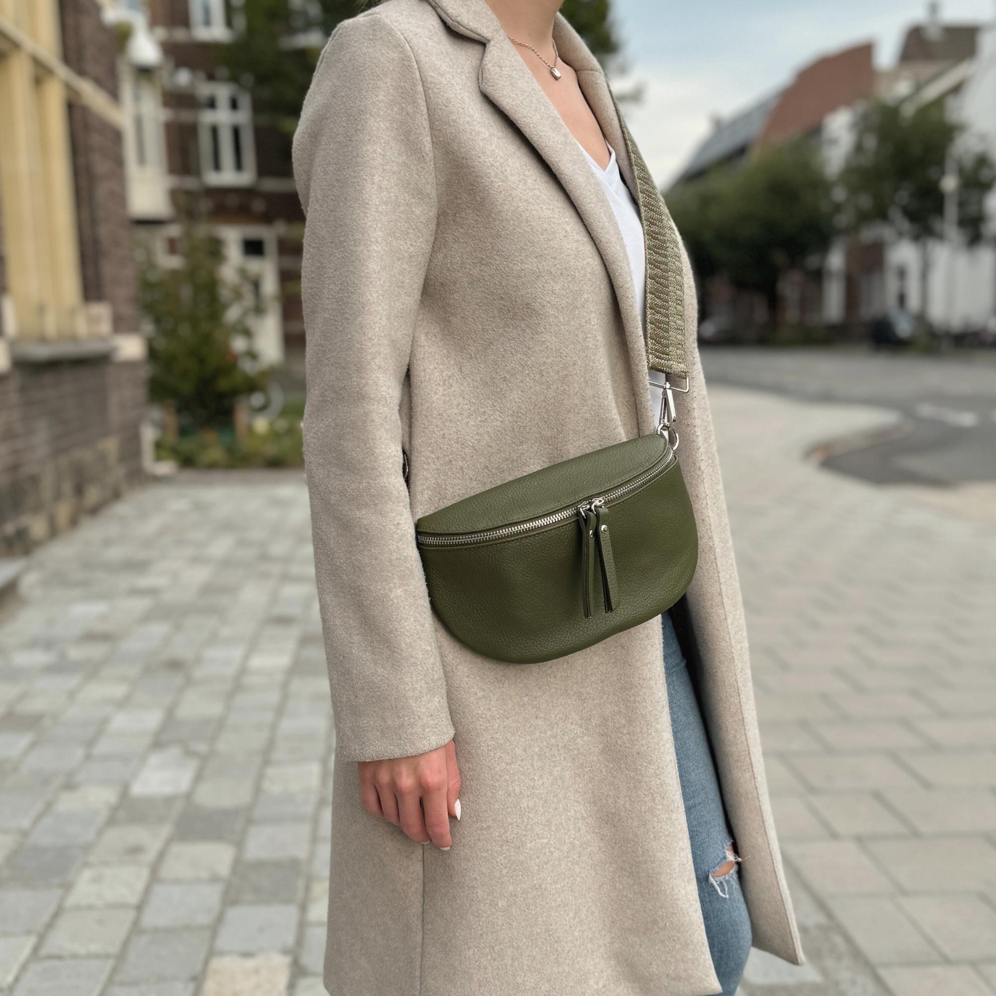 dunkelgrüne Bauchtasche aus Leder präsentiert in urbaner Umgebung von Frau mit beigen Mantel.