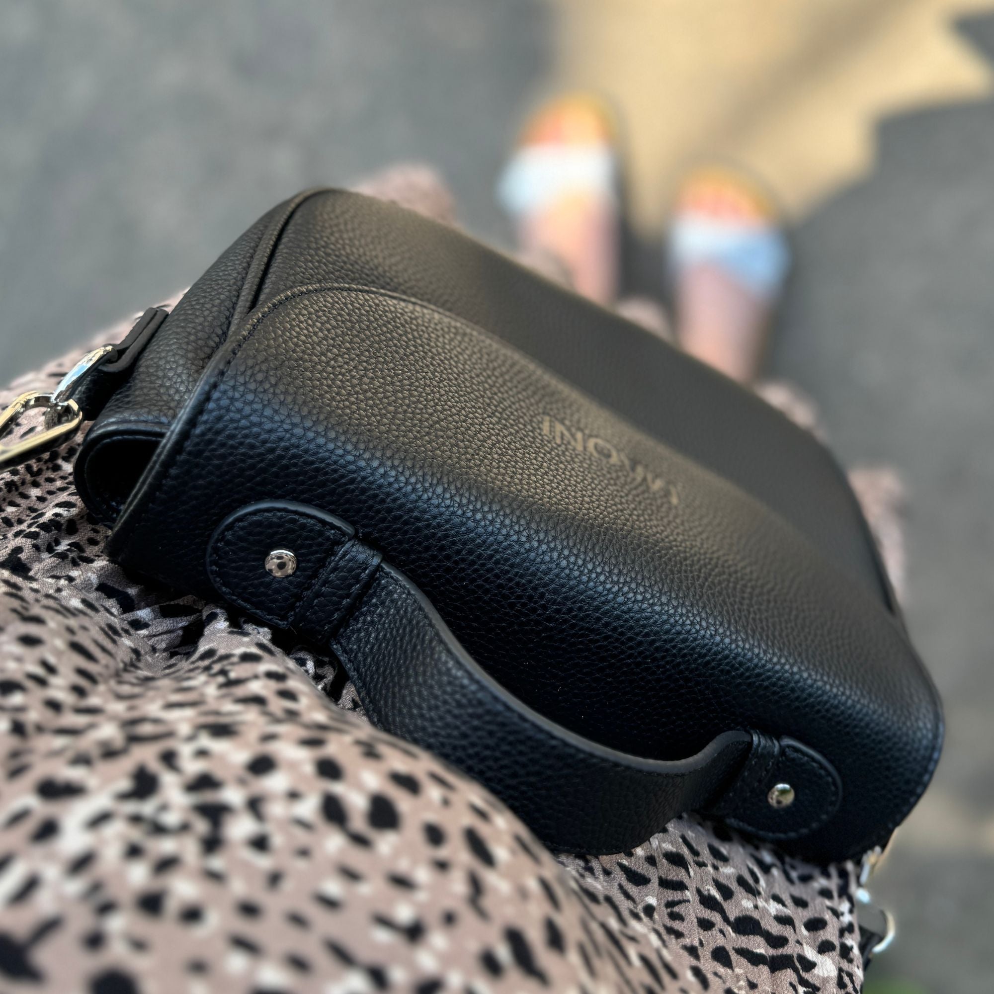 Top-Down-Perspektive: Frau trägt schwarze Halfmoon-Tasche zusammen mit einem Leo-Kleid und Sandalen.