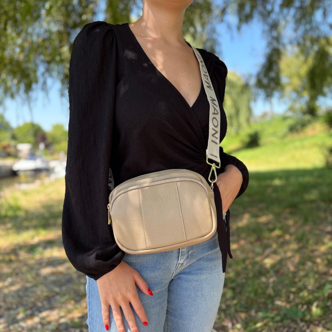 Frontansicht einer taupen Crossbody-Tasche, getragen von einer Frau mit Wickelbluse – stilvoller Look für jeden Tag