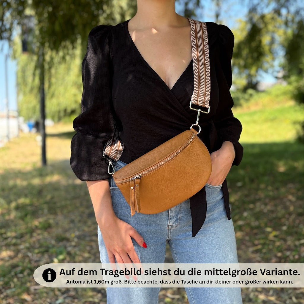 Cognacfarbene Leder-Bauchtasche für Damen mit auffälligem gezacktem Gurt – von einer Frau lässig getragen