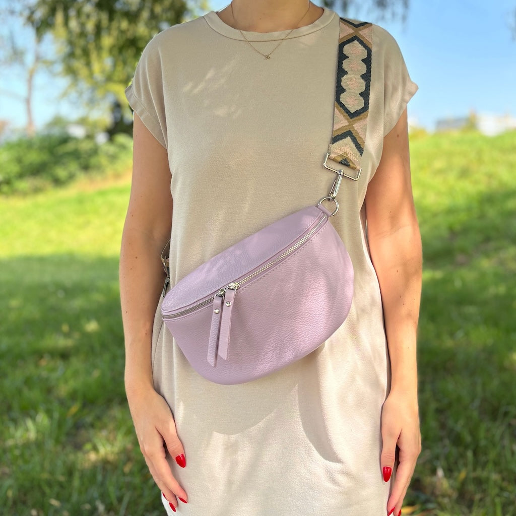 Bauchtasche in der Farbe Lila kombiniert mit breitem Stoffgurt. Getragen wird die Bauchtasche von junger Frau.