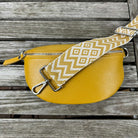 Hochwertige Leder-Bauchtasche in Gelb mit breiten Schultergurten, gefertigt in Italien, auf einem Holztisch.