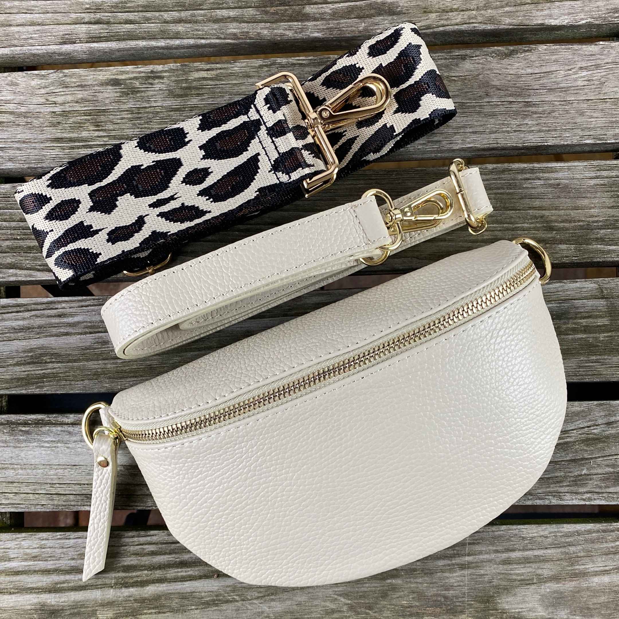 Leder-Bauchtasche in Beige mit Leo-Gurt, gefertigt in Italien, präsentiert auf einem Holztisch. Stylisches Taschen-Set von MAONI - mit goldenen Verschlüssen.