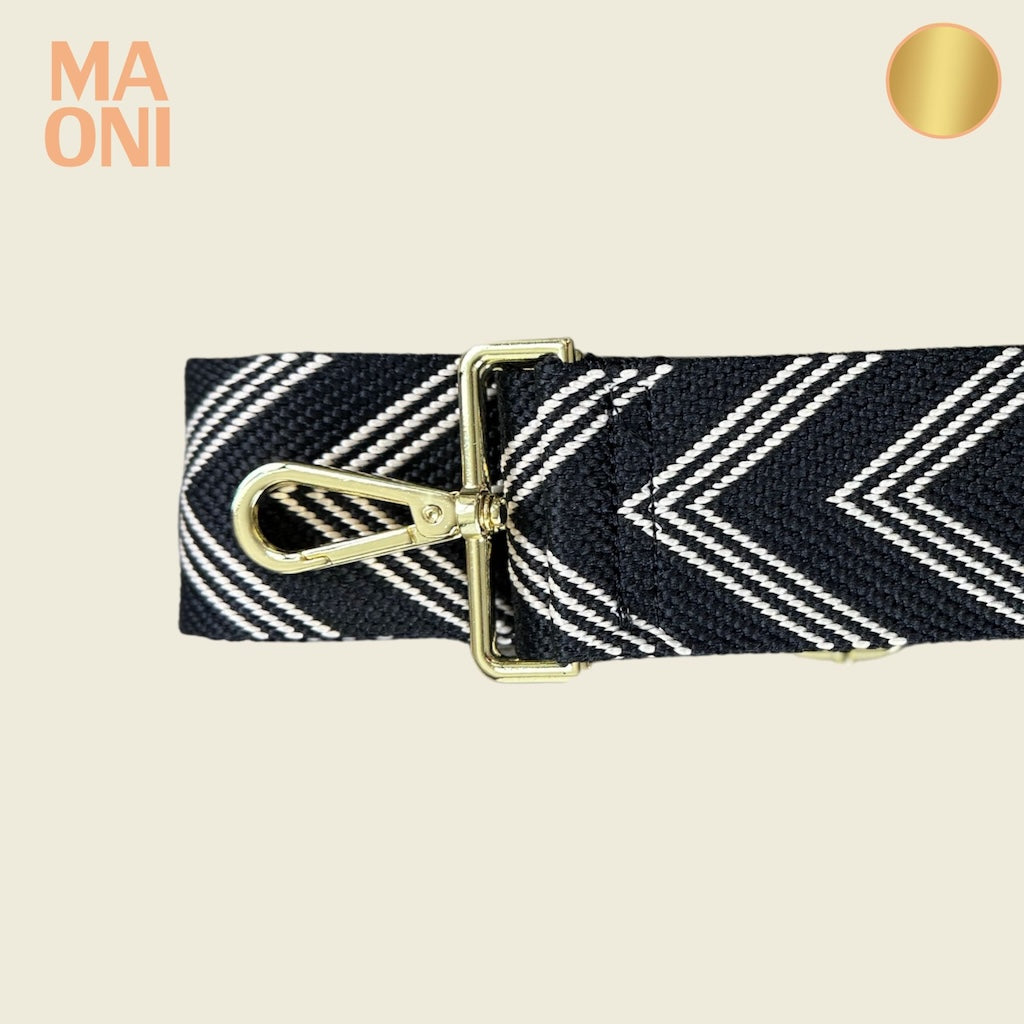 Taschengurt mit goldenem Verschluss in den Farben schwarz beige. Gurt ist ausgeschnitten auf beigem Hintergrund.