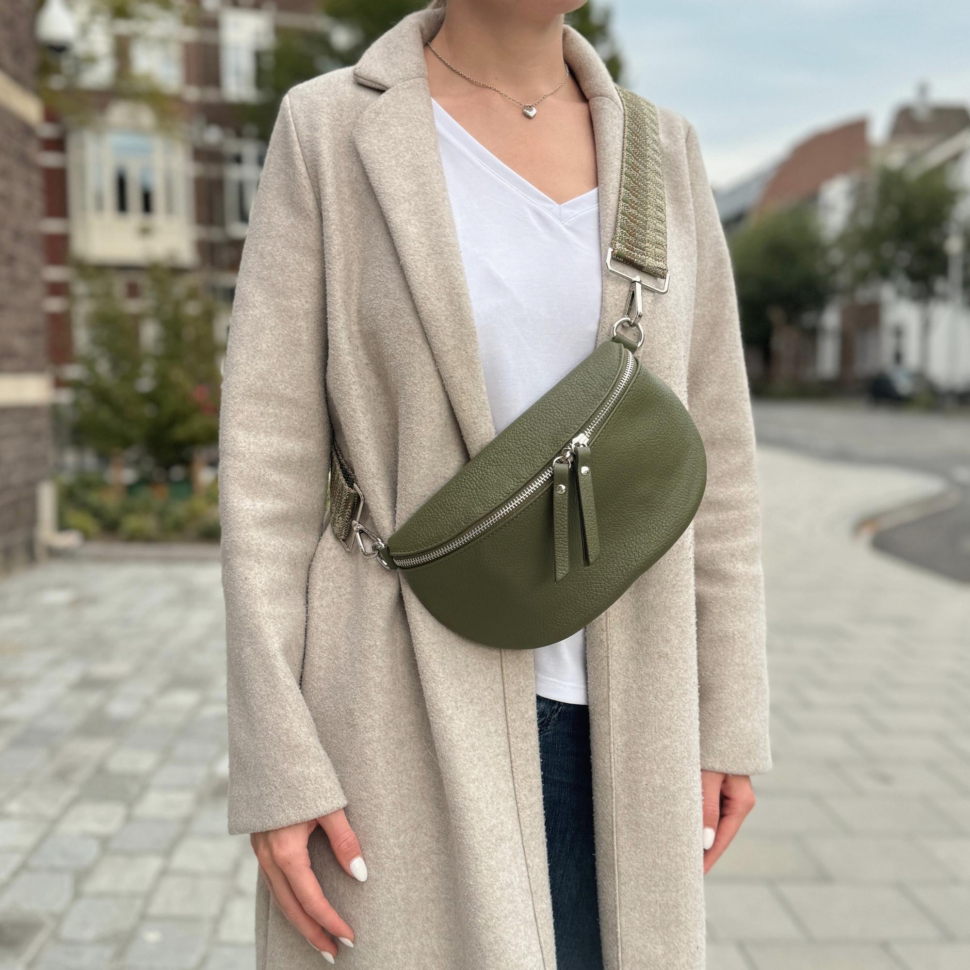 Frau mit herbstlichen Outfit präsentiert eine Dunkelgrüne Bauchtasche aus Leder.