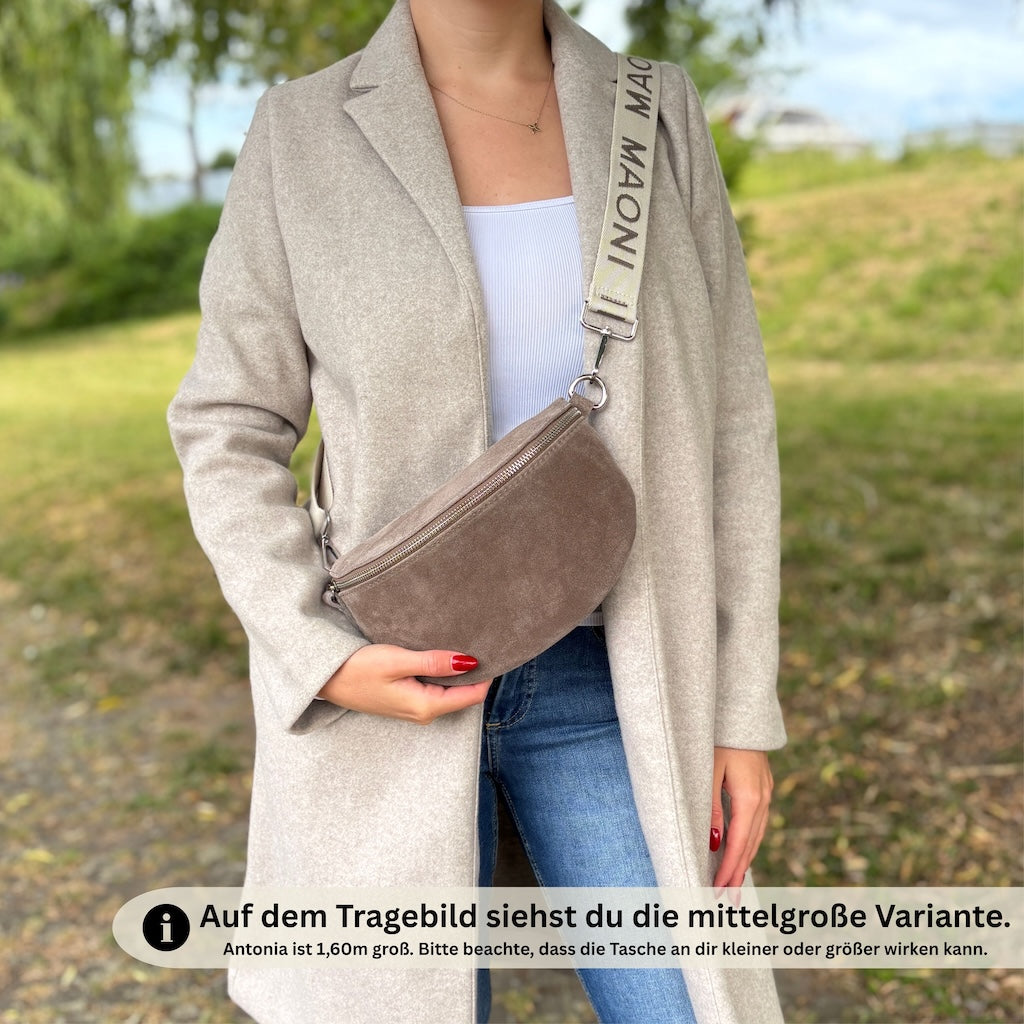 Mittelgroße Wildleder-Bauchtasche für Damen, crossbody getragen von Frau im beigen Mantel – kombiniert mit zweifarbigem MAONI-Wechselgurt