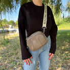 Damen-Crossbody-Bag in natürlicher Umgebung kombiniert mit Jeans und schwarzem Pullover