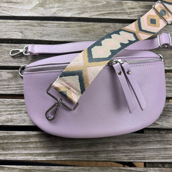 Variantenbild auf Holz: MAONI-Bauchtasche in Lila, dazu schmaler Leder- und breiter Muster-Gurt in den Farben grau, braun, rosa im Flatlay